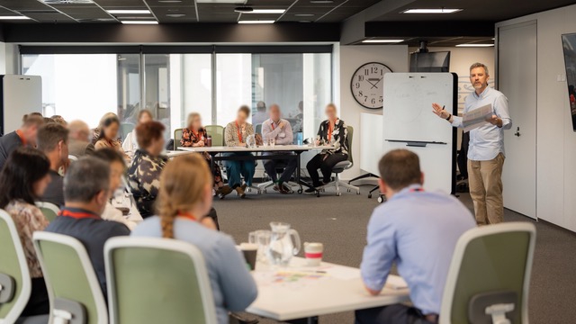 A facilitator working at a whiteboard with a seated group
