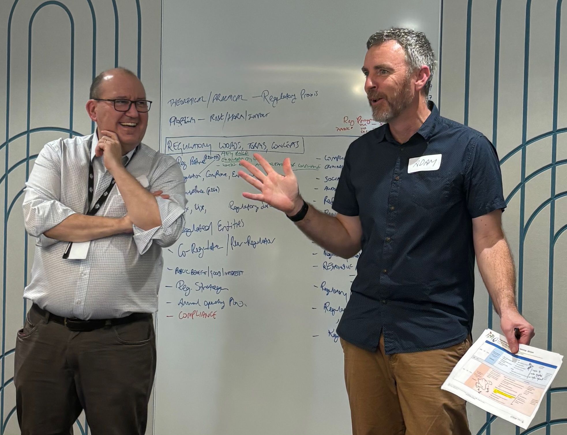 Grant Pink and Adam Beaumont in discussion at a whiteboard mapping regulatory words, terms and concepts